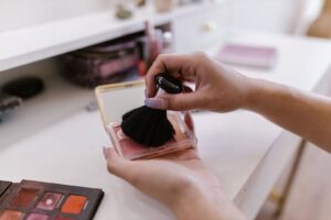 Sminkborste sveper över en palett med rosa rouge vid makeupbordet