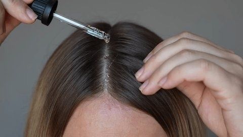 Person applicerar serum med pipett direkt i hårbotten